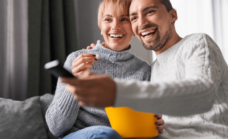 Happy couple watching convenient television service at hotel