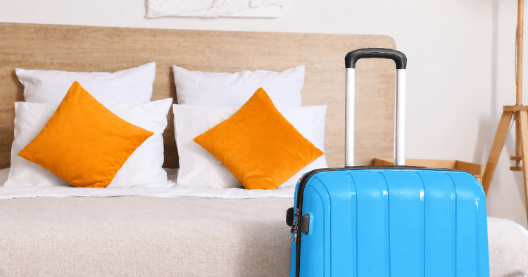 Hotel guest suitcase next to bed after checking in easily