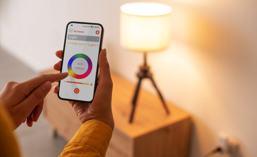 Woman controlling smart lighting at home, she is setting light color using her smartphone
